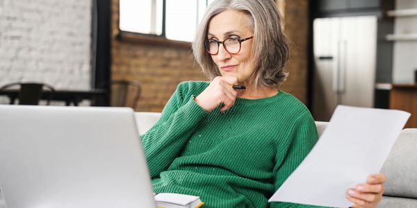 A woman sitting on a couch looking pensively at her computer