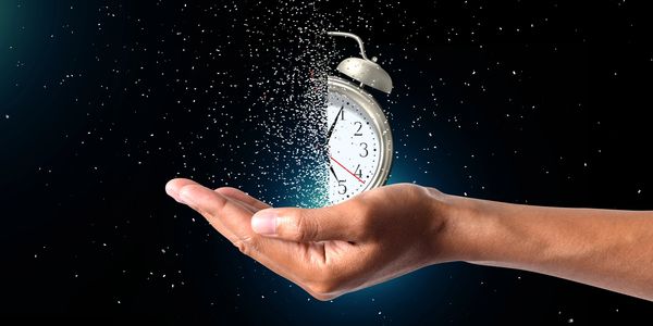 A hand holding a dissolving clock