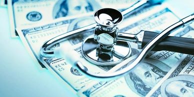 A photograph of a stethoscope laying on a pile of cash money