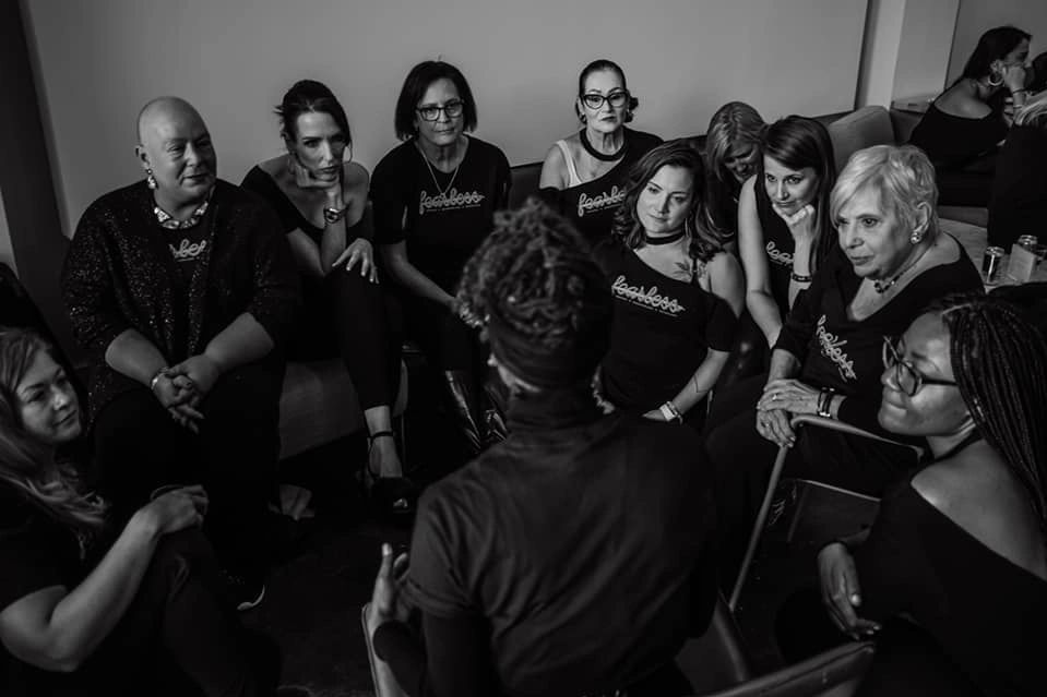 A group of breast cancer survivors encircles Lolita during a Strut Talk Runway Therapy session.