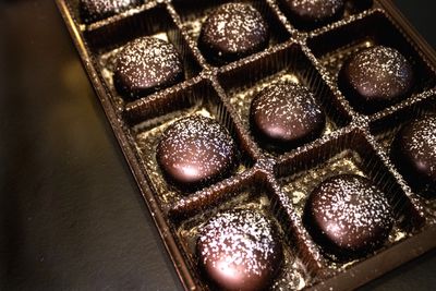 Box of round chocolate truffles dusted with powdered sugar.