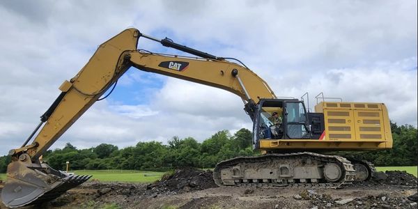 Image of a large excavator in Columbus Ohio excavating a job site in a forested area.
