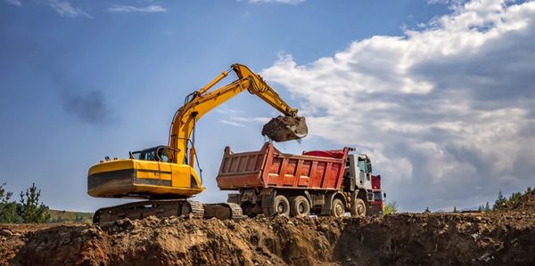 Excavator in Columbus Ohio dumping dirt into a dump truck as it prepares land for construction