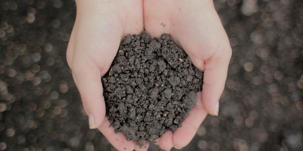 Photo of hands holding asphalt millings with asphalt millings in the background in Columbus Ohio