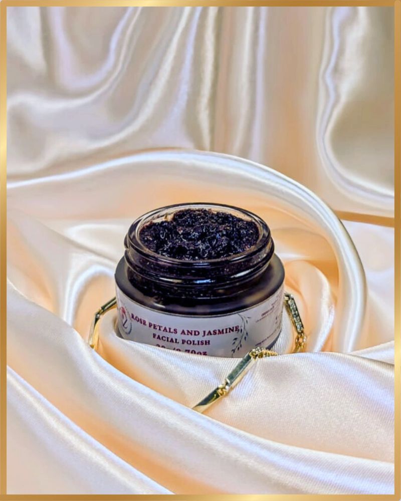Jar of rose petals and jasmine facial polish on silky fabric.
