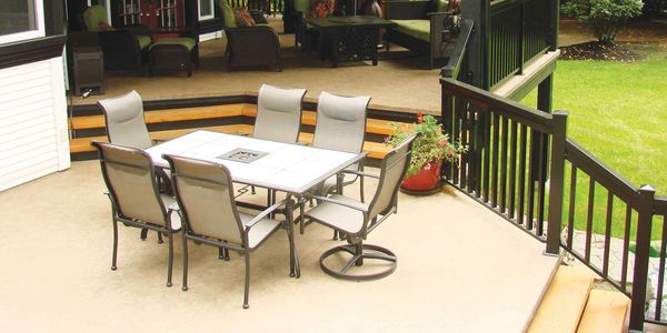 Spacious outdoor patio with dining and lounge areas surrounded by greenery.