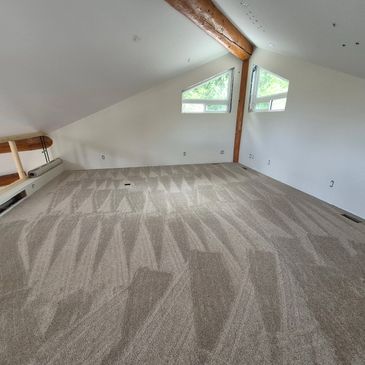 Empty attic room with new patterned carpet and white walls.