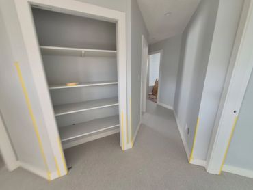 Empty hallway with built-in shelves and gray walls.