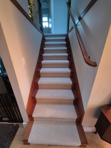 Carpeted stairs with wooden edges and a handrail on the right.