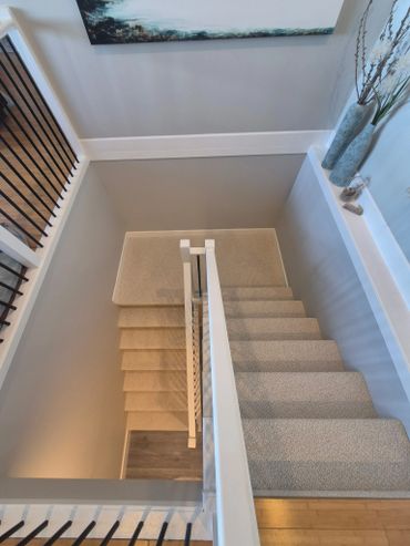 Top view of carpeted stairway with white railings and decorative vases.
