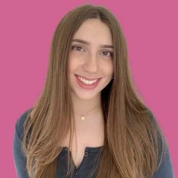 Smiling young woman with long hair against a pink background.
