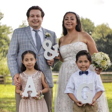 Just married couple poses with their young children.  Building beautiful memories, a family united.