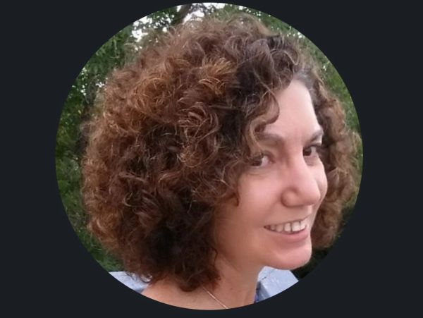 Smiling woman with curly hair outdoors.