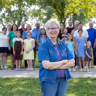 Smiling elderly woman standing confidently with family behind her.