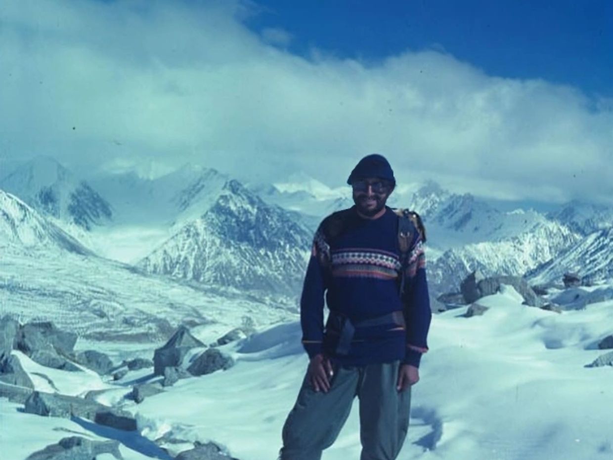 Man in winter clothing standing in snowy mountain landscape.
