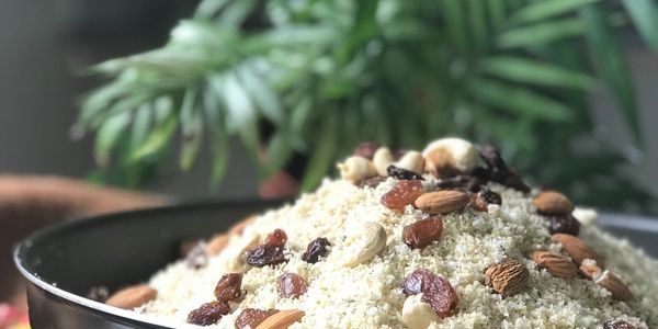 Bowl of couscous topped with mixed nuts and raisins.
