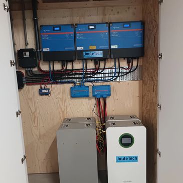 Electrical control panel with JouleTech branded devices mounted on a wooden board.