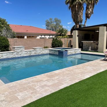 Modern backyard pool with spa and lounge area under clear blue sky.