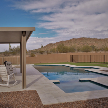 Backyard pool area with chairs and desert hills in the background.