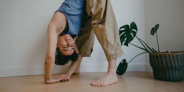 Person in casual clothes bending backward with hands on the floor in a bright room.