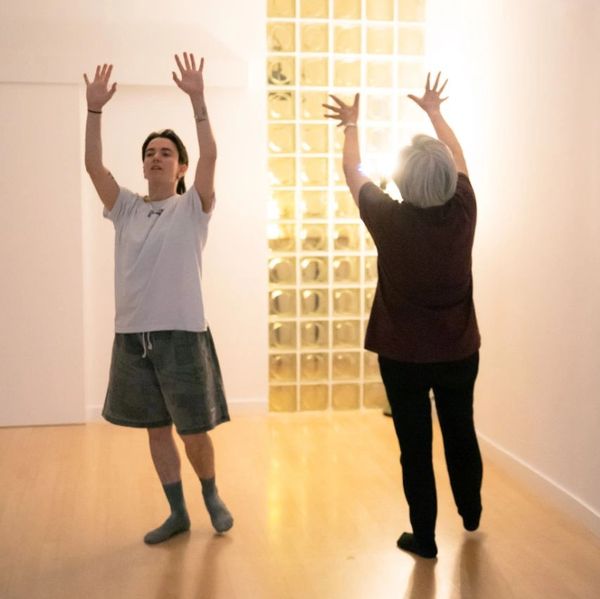 Two people practicing a stretching or dance exercise indoors.