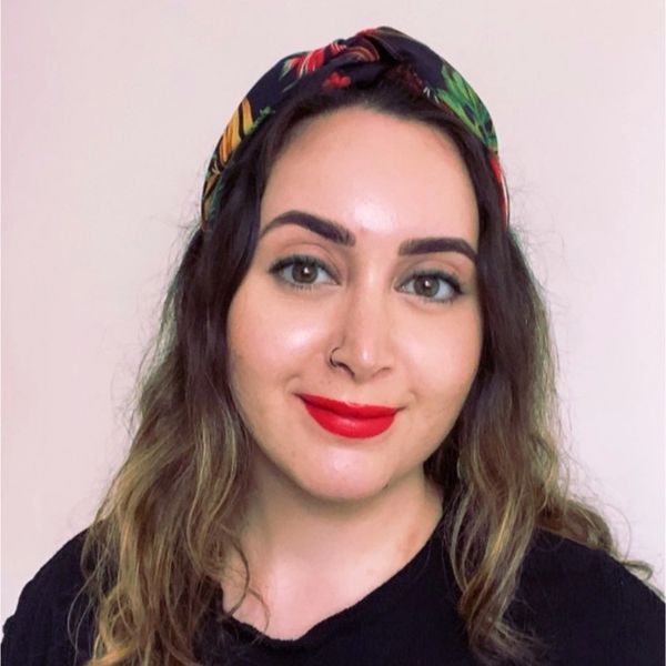 Young woman with red lipstick and floral headband smiling.