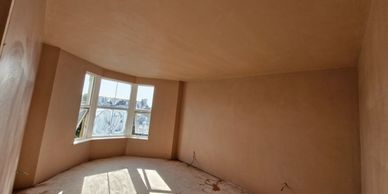 Empty room with freshly plastered walls and bay window.
