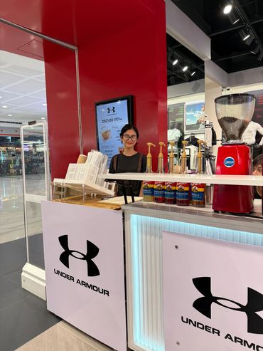 Woman behind an Under Armour coffee counter.