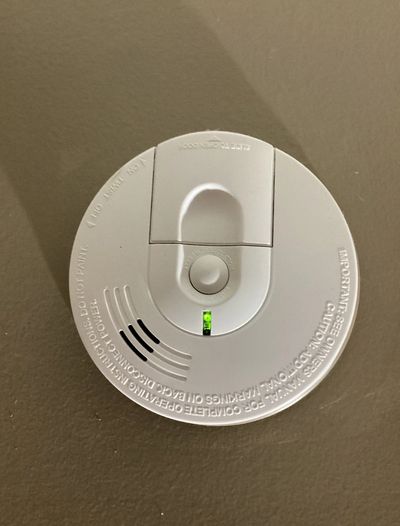 A smoke detector with a green light illuminated.