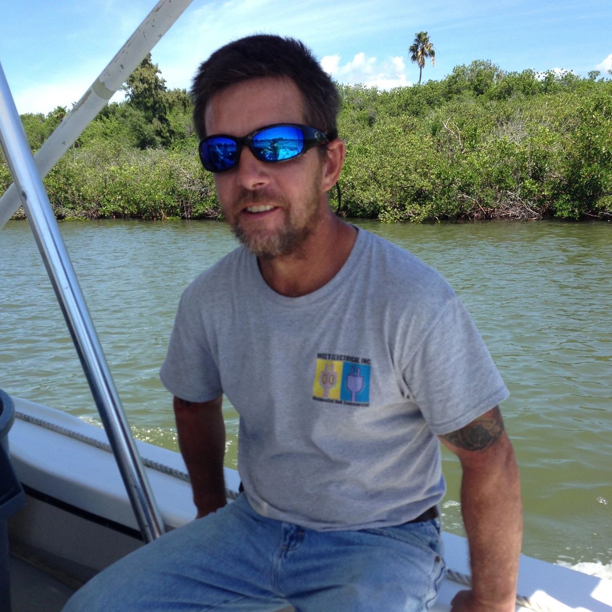 Man wearing sunglasses on a boat by the water.
