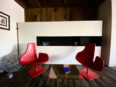 Dark brown/gray floors with red chairs with white and wood planked walls in the background