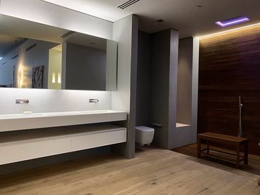 Bathroom remodel with light tan floors, white countertops with a two sink bathroom, and gray walls