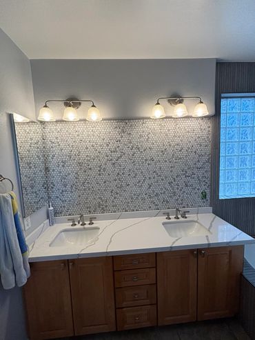 Bathroom remodel with dark brown cabinets and white quartz countertops with gray veins throughout