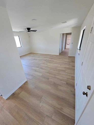 Bedroom remodel with light tan flooring and white walls, with a black fan on the ceiling