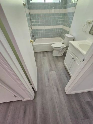 Bathroom remodel with light gray floor and blue backsplash in shower with white vanity