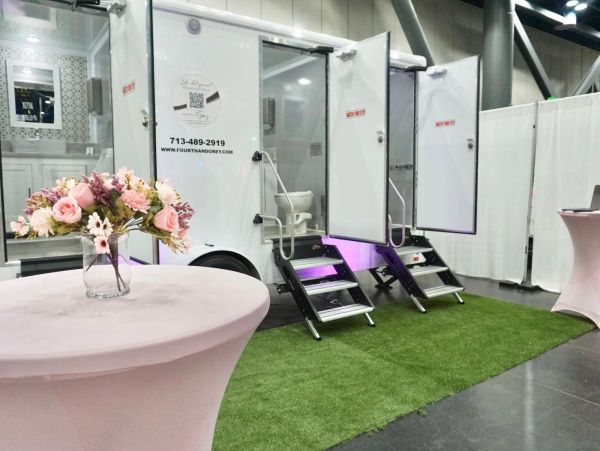 Luxury portable restroom trailers with floral decorations at an event.
