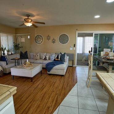 Cozy living room with beige sectional, wooden floor, and tiled dining area.