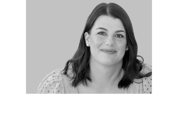 Smiling woman with dark hair in a pink blouse against a light purple background.