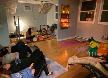 People relaxing in a cozy meditation room with candles and soft lighting.