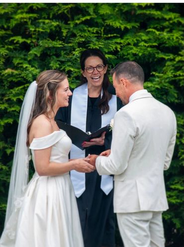 Bride and groom exchanging vows with officiant during outdoor wedding ceremony.
