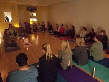 Group meditation session with candles in a softly lit room.