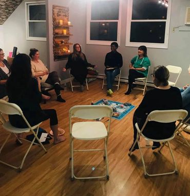Group of people seated in a circle having a discussion in a cozy room.