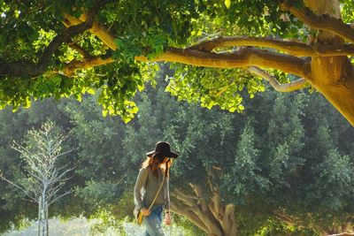 Woman walking under green trees