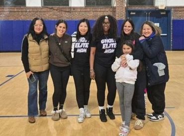 A group of women and a child posing together in a gymnasium.
