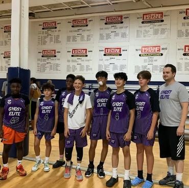 Youth basketball team Ghost Elite posing in gym with coach.