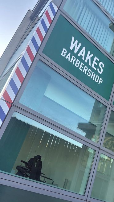 Exterior view of Wakes Barbershop with a classic barber pole design.