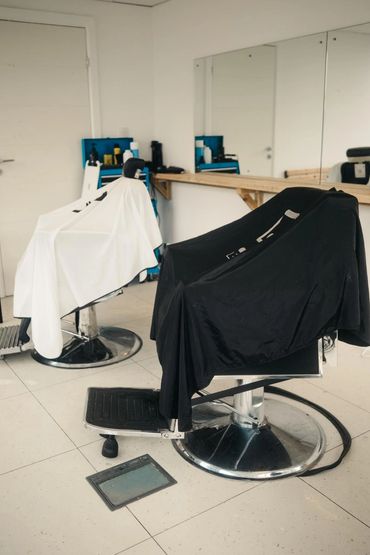 Two barber chairs with black and white capes in a minimalist salon.