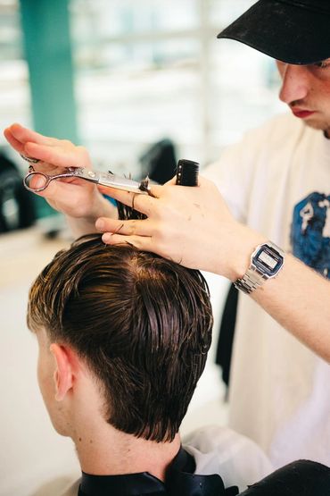 Barber cutting a client's hair with scissors and comb.
