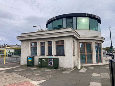 A unique round building with a glass upper floor and concrete lower floor on a street corner.
