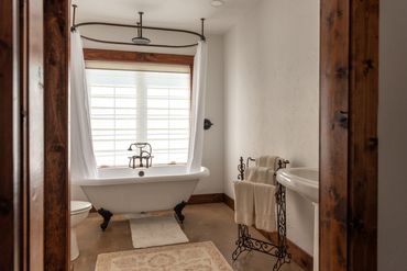 A victorian claw foot tub in a bathroom with white walls and stained wood accents